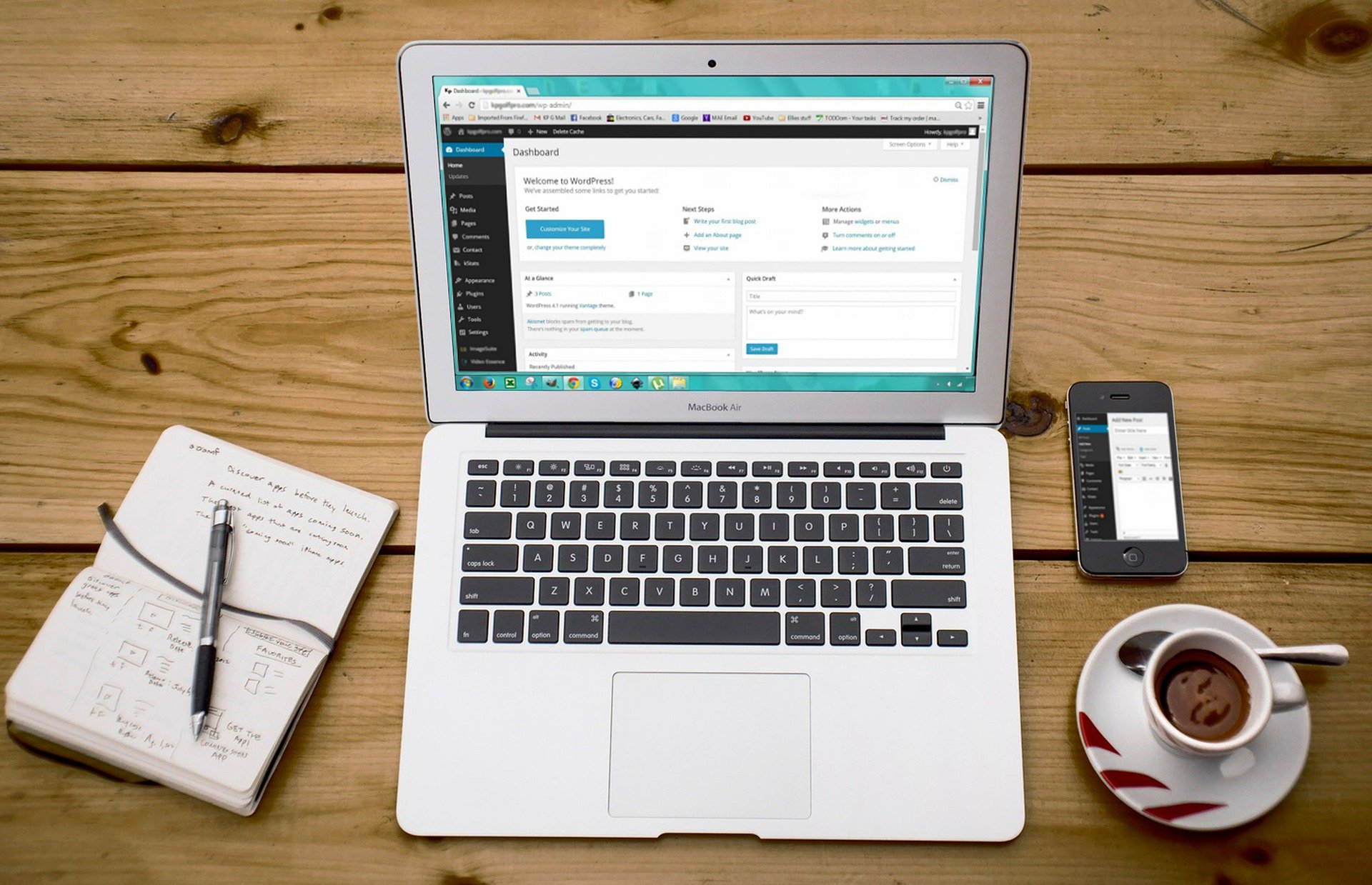 laptop, coffee, cell phone and notepad with pen on wooden table